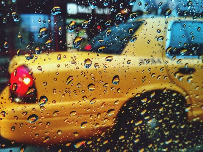 View of yellow car across wet glass