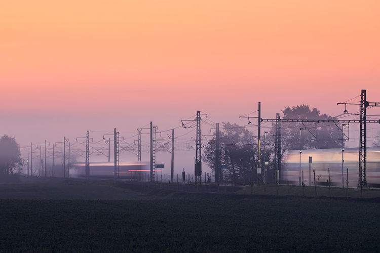 Traffic on electrified railroad track at foggy autumn morning. trains in blurred motion.