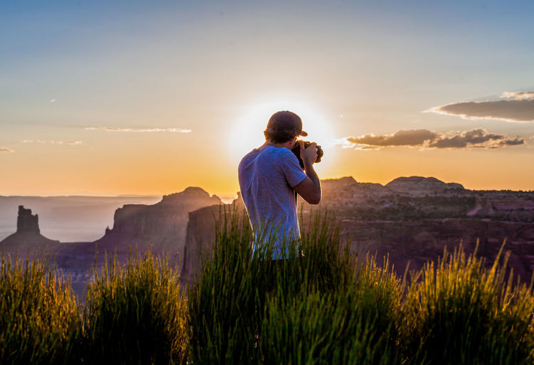 Rear view of man photographing during sunset