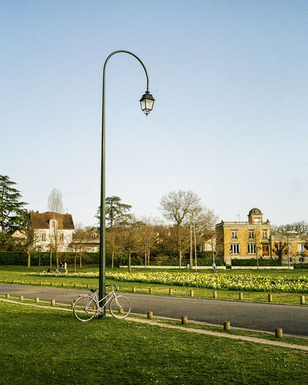 Street light on field by building against clear sky