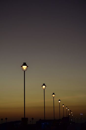 Low angle view of street lights against sky at sunset
