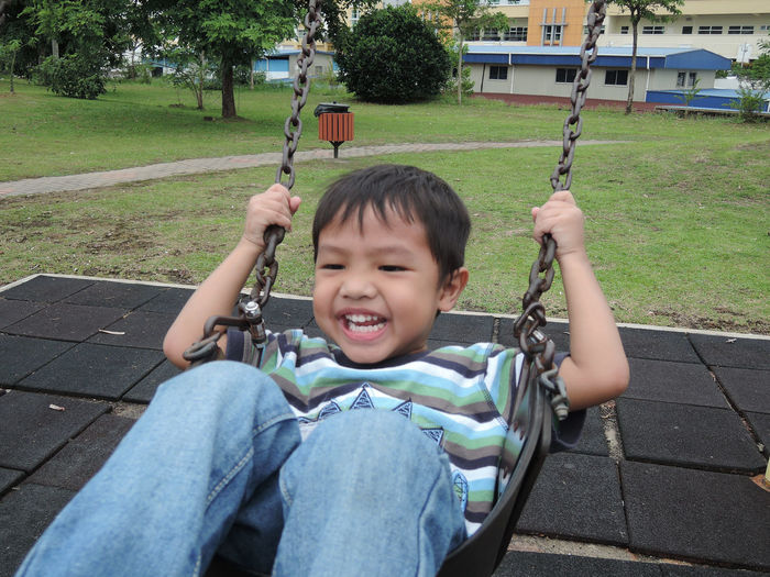 Portrait of smiling boy on swing at park