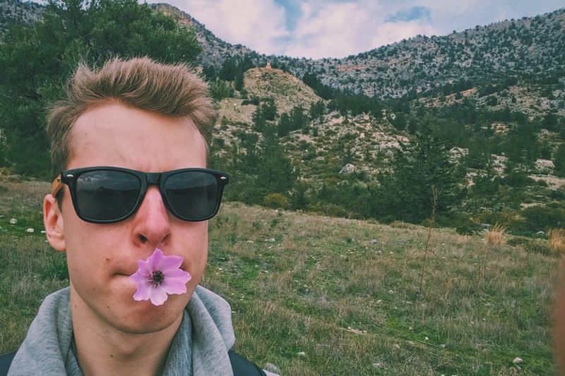 Close-up of man with flower in mouth on mountain landscape