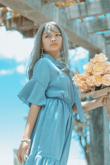 Young woman standing against blue sky