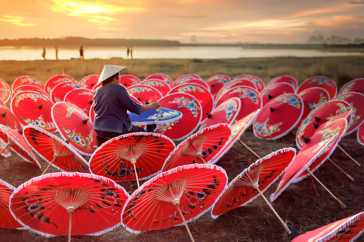 Full length of man sitting on beach against sky during sunset