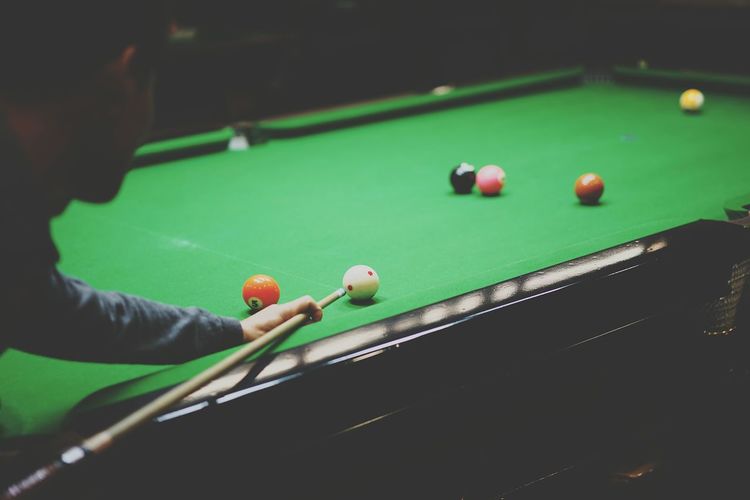 Cropped man aiming ball at pool table
