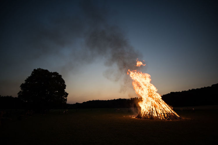 Bonfire on field against sky at night