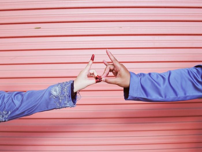 Cropped image of couple joining hands against shutter