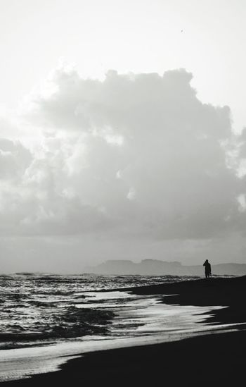 Silhouette person looking at sea against sky