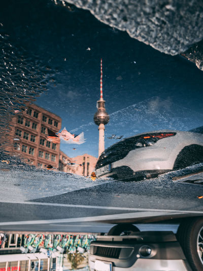 Reflection of fernsehturm on puddle in city
