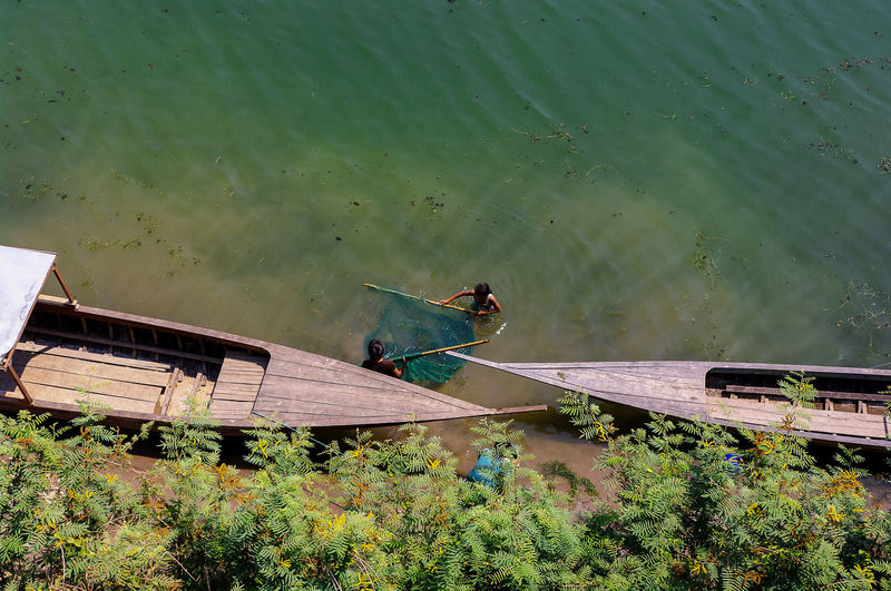 High angle view of women fishing by boats in lake