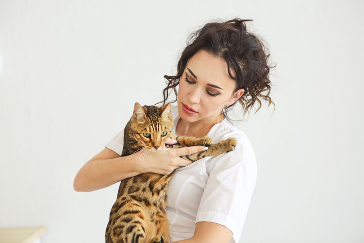 Portrait of a young woman with cat against white background