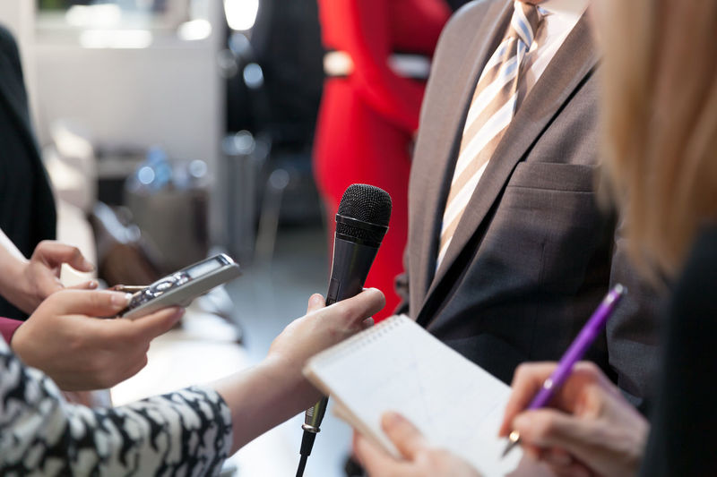Cropped hand holding microphone while interviewing businessman