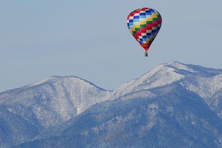 Hot air balloons flying in mountains against sky
