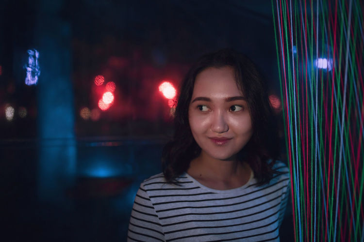Cheerful optimistic asian girl smiling, neon light background