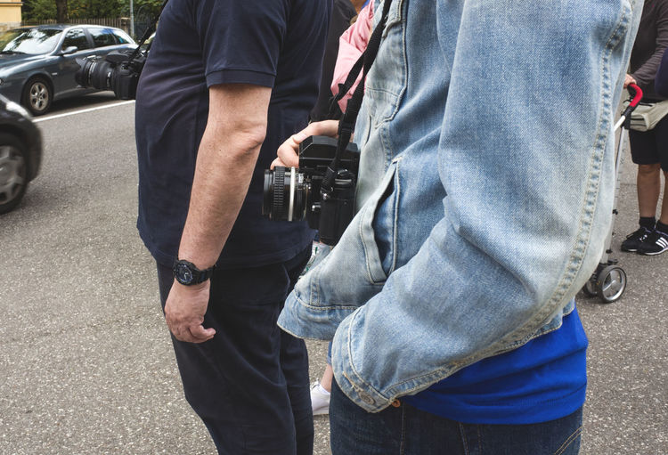 Midsection of woman with digital camera standing on street