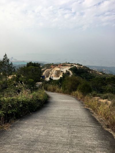 Road leading towards cliff against sky