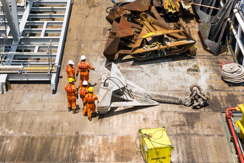 A team of riggers preparing anchor on deck of a construction work barge at offshore oil field