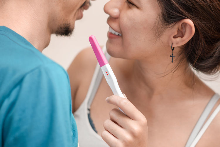 Woman holding pregnancy test while embracing man