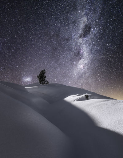 Scenic view snow covered hills against star field at night