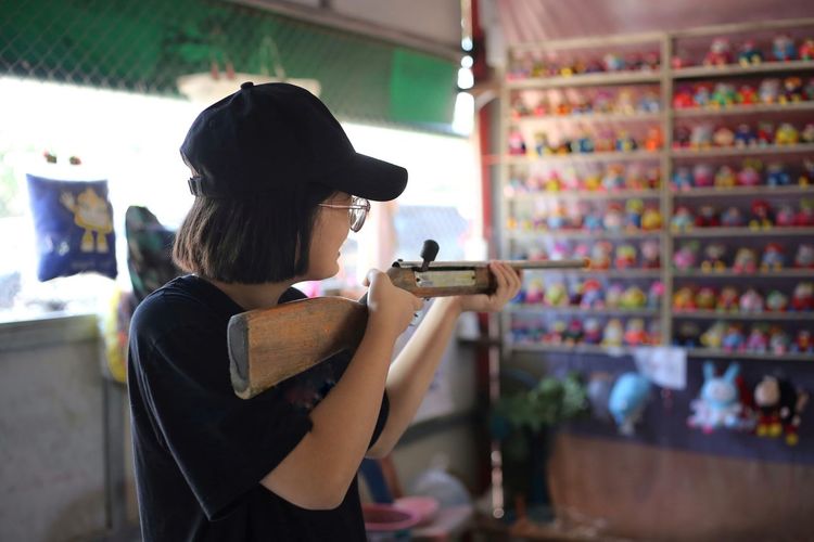 Side view of girl aiming gun at store