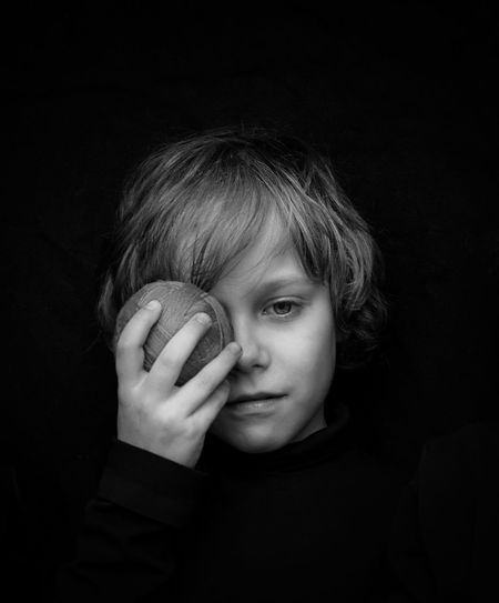Portrait of boy holding jarn ball against black background