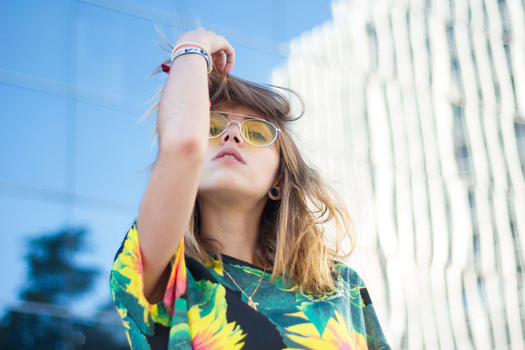 Portrait of young woman wearing sunglasses against building