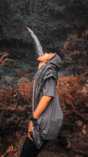 Optical illusion of man drinking water falling from rock in forest