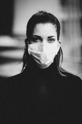 Close-up portrait of young woman wearing chirurgical mask.