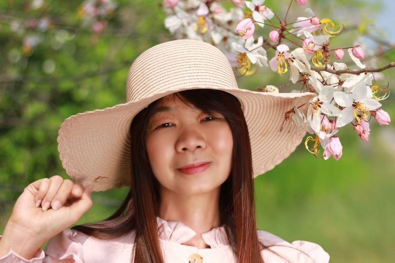 Portrait of smiling woman wearing hat against plants