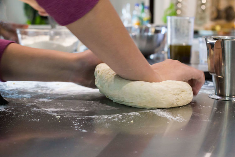 Cropped hands of dough kneading on table