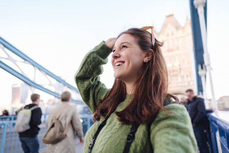Happy young woman taking selfie on tower bridge, london, england