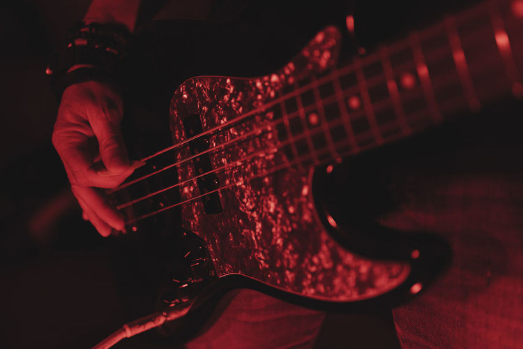 Close up of an anonymous man playing guitar in red light