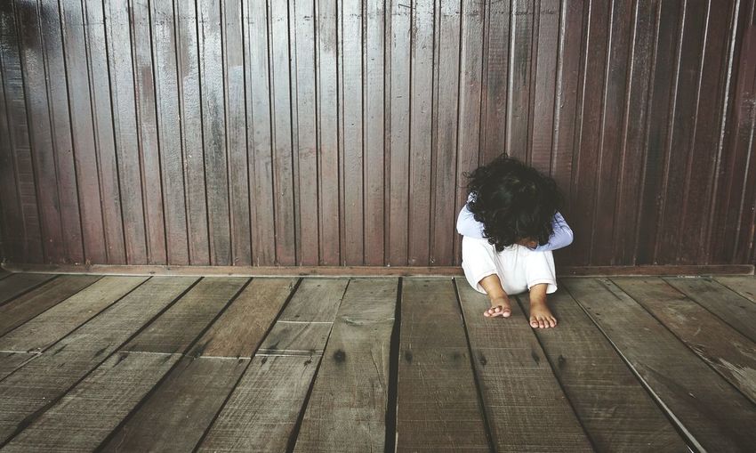 Child sit on the wooden floor. 