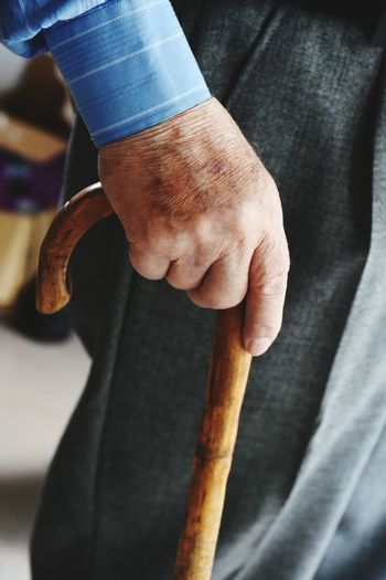 Midsection of a senior man holding walking cane