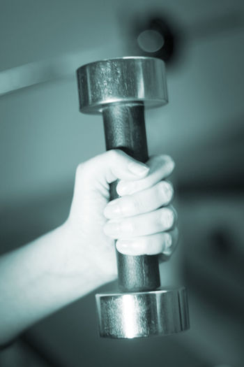 Cropped hand lifting dumbbell in gym