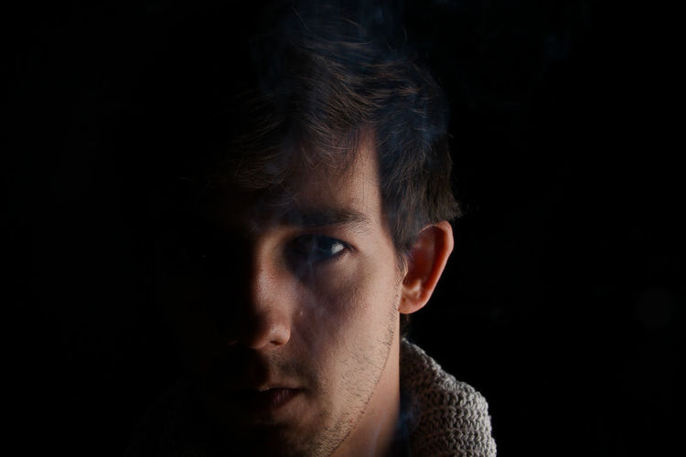 Close-up portrait of mid adult man against black background