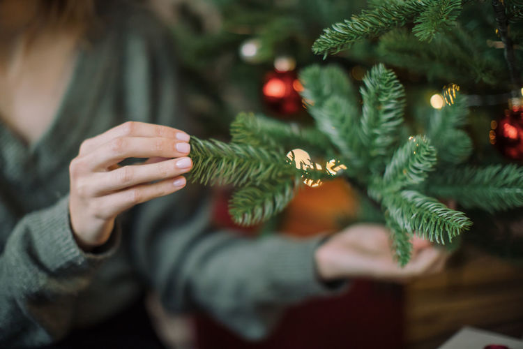 Midsection of woman touching christmas tree at home