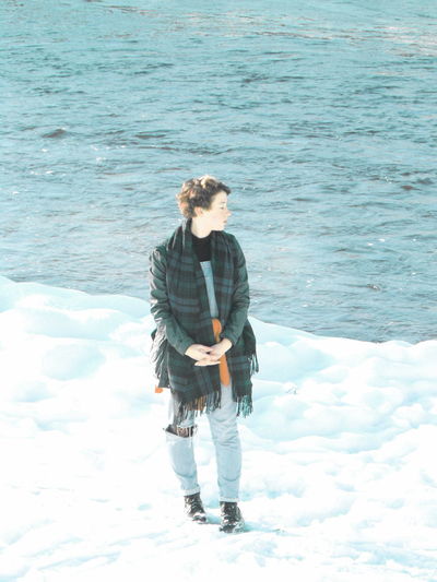 Full length of teenage girl standing on snow by sea