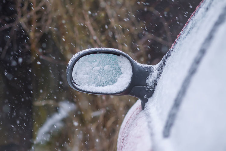 Car wing mirror covered up with fresh wet snow.