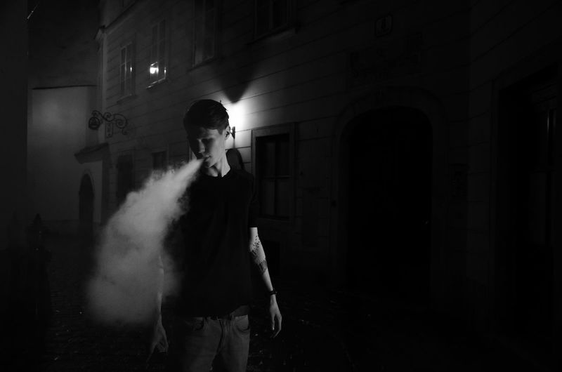 Man exhaling smoke at night