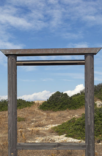 Scenic view of field by sea against sky