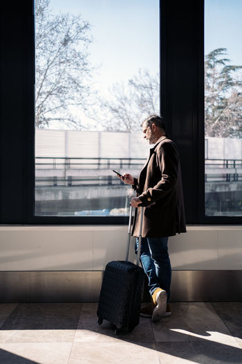 Full length of man using phone on window