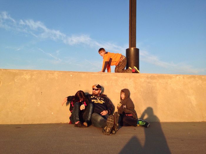 Father with kids sitting against sky