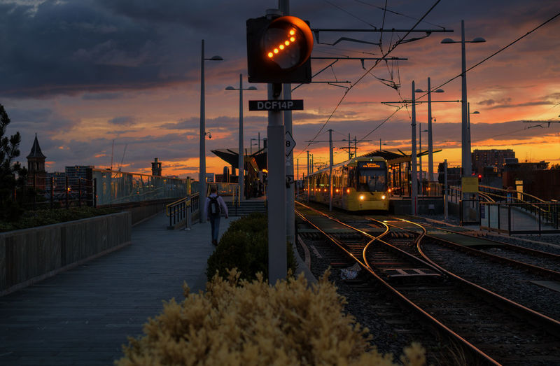 Train on railroad tracks against sky during sunset