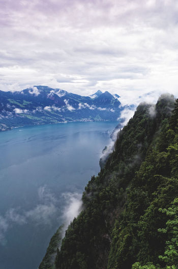 Scenic view of mountains and sea against cloudy sky