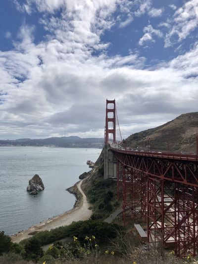 Golden gate bridge over sea against cloudy sky