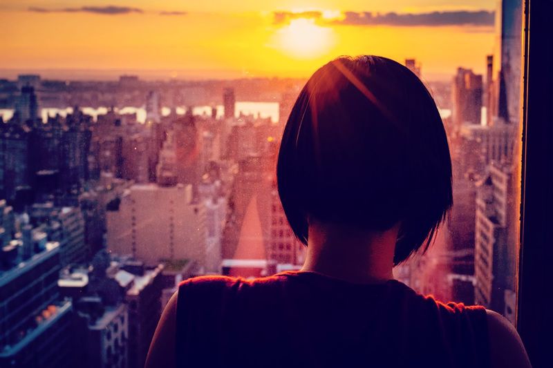 Rear view of silhouette man against cityscape during sunset