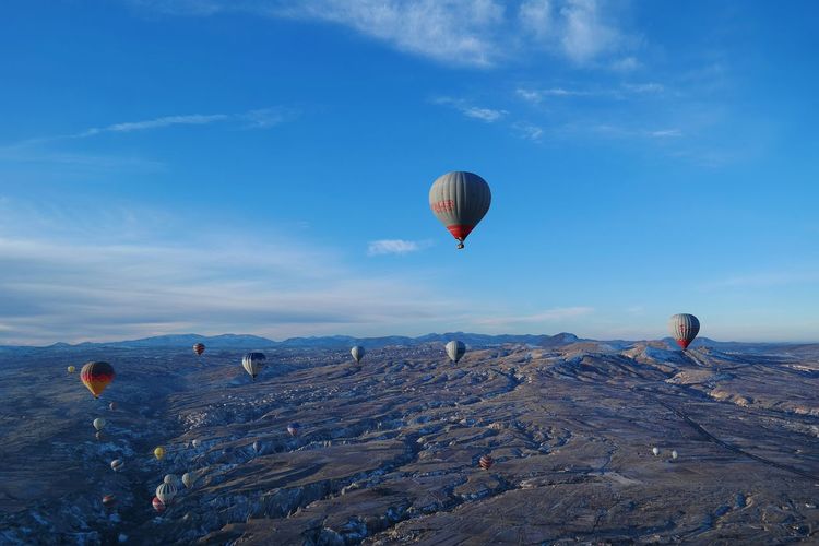 Hot air balloons flying over cappadocia against blue sky