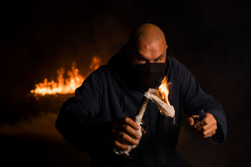 Midsection of man holding fire against black background